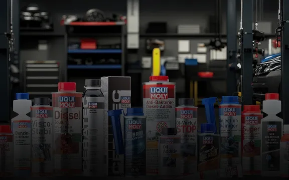 A variety of Liqui Moly automotive additives and cleaners standing in a blurred professional garage workshop.